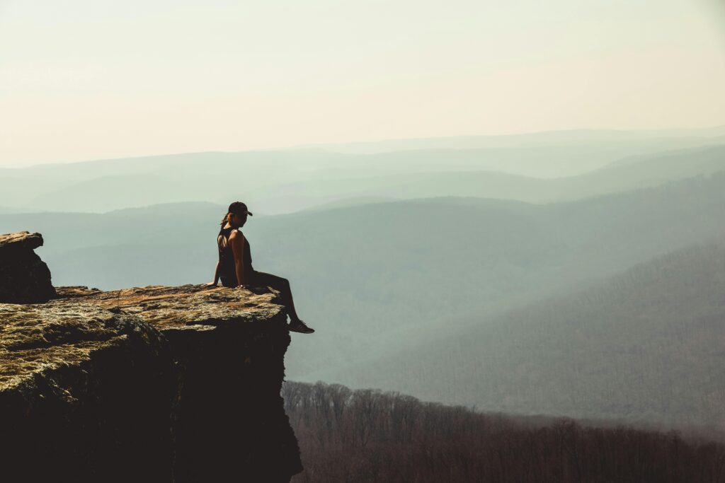 woman dangling legs off rock